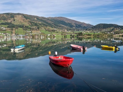 Boats on the calm lake Hafslovatnet, mountains reflected in the lake, Sognefjord region, Norway,