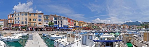A picturesque harbour with numerous boats, colourful buildings and restaurants under a blue sky