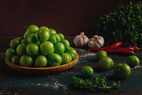 Tkemali, green cherry plum, with ingredients for sauce, cilantro, mint, hot pepper, garlic, on a