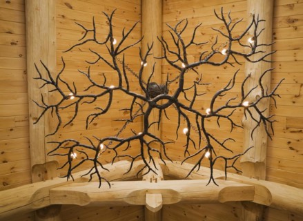 Illuminated deer antlers chandelier hanging from high cathedral knotty pine wood planks ceiling,