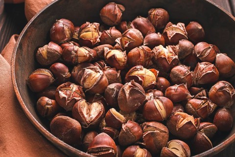 Roasted chestnuts, in an iron pan, wooden table, top view, no people, rustic style