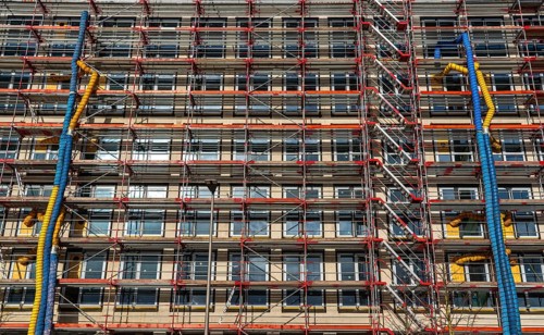 Large construction site, scaffolded shell of an office building complex, air hoses for building