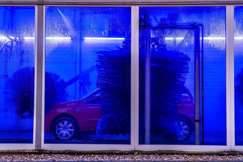 Car in an automatic car wash, car wash tunnel, cleaning foam is sprayed on, rotating brushes clean