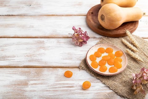 Jelly pumpkin candies on white wooden background and linen textile. copy space, side view. autumn