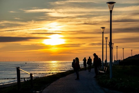 Sunset on the beach of Zoutelande, people on the dike, Zeeland, Netherlands