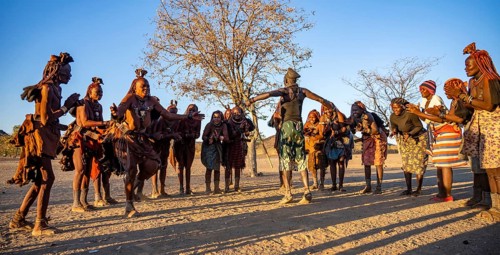 Group of traditional Himba woman with Cief of the village standing in a semicircle, clapping and