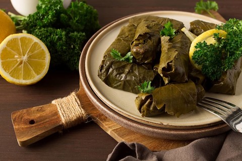 Dolma, cabbage rolls, grape leaves with filling, white sauce, lemon and herbs, rustic, selective