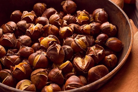 Roasted chestnuts, in an iron pan, wooden table, top view, no people, rustic style