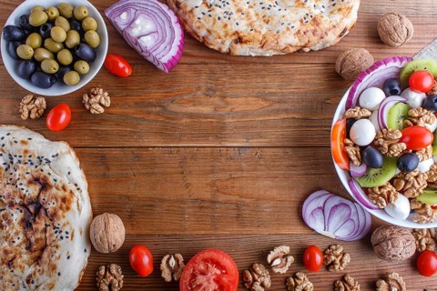 Frame made from cherry tomatoes, mozzarella cheese, olives, kiwi, onion and walnuts on brown wooden
