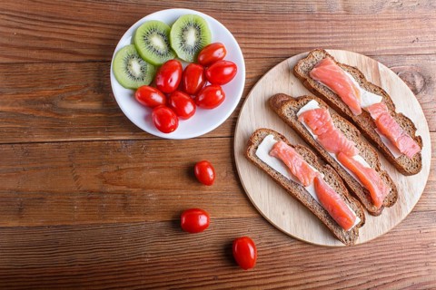 Smoked salmon sandwiches with butter on wooden background. cherry tomatoes. top view, copy space