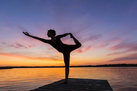 Woman practicing yoga posture Natarajasana, Lord of the Dance Pose, one legged standing, balancing,