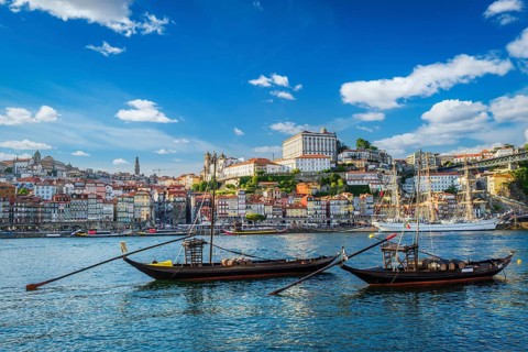 View of Porto city and Douro river with traditional boats with port wine barrels and sailing ship