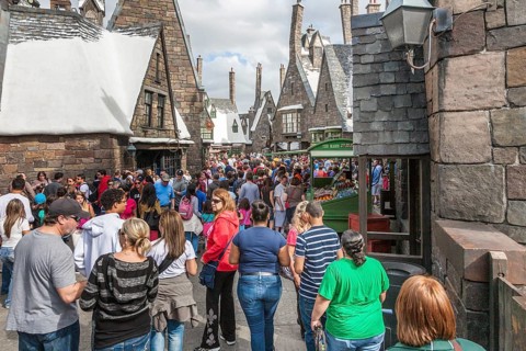 Theme park guests walk through Hogsmeade in The Wizarding World of Harry Potter at Universal
