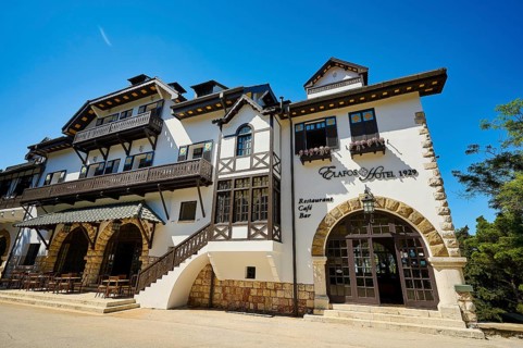 Historic white hotel with half-timbered walls, balconies and parasols on a sunny day, Elafos Hotel,