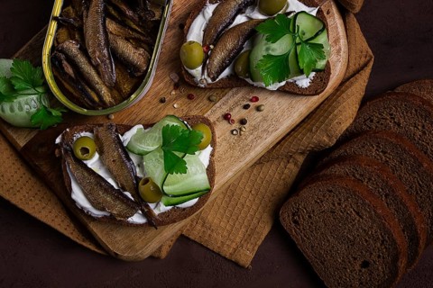 Sandwiches, black bread with sprats, cream cheese, cucumbers, on a cutting board, top view,