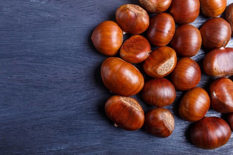 Pile of sweet chestnuts on black wooden background with copy space, top view