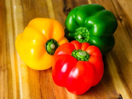 Close-up, yellow, red, green peppers (Capsicum annuum) on wooden board