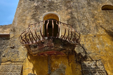 An abandoned balcony with a rusty railing on an old, weathered wall, Italian Governor's Palace,