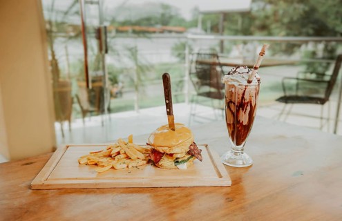 Classic burger with fries and milkshake on wooden board with copy space. Big hamburger with fries