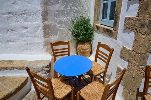 Cosy scene with wooden chairs and a round table in a Mediterranean setting, Chora, main town of