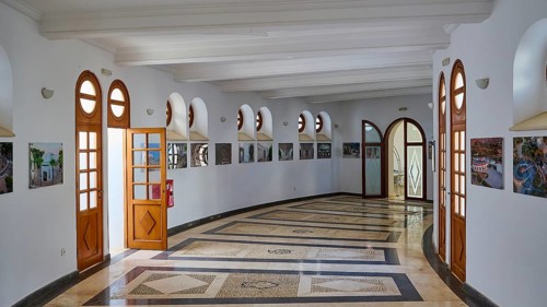 Light-flooded hallway with marble floor and wooden doors, decorated with square windows and