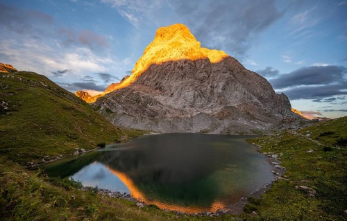 Alpenglow at Seekopf or Monte Capolago, reflection in Wolayersee, mountain landscape with green