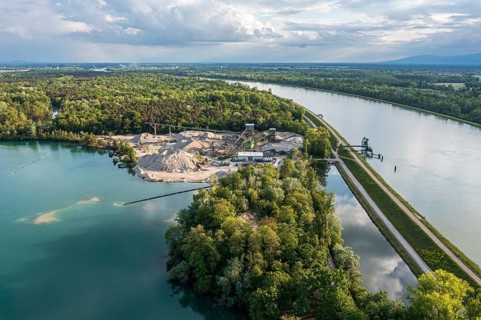 Aerial view of turquoise quarry pond of a gravel pit, excavation and loading area at the Rhine