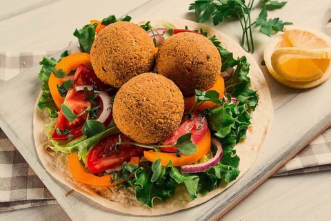 Tortillas, wrapped falafel balls, with fresh vegetables, vegetarian healthy food, on a wooden white