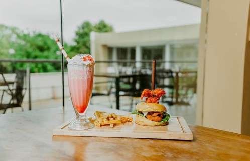 Traditional chicken burger with french fries and strawberry milkshake on restaurant table.