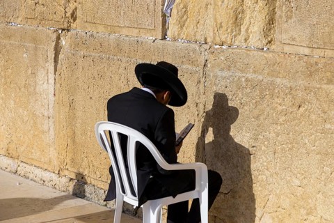Orthodox jew is praying in front of Sacred Western Wall in Jerusalem Old City Jewish Temple