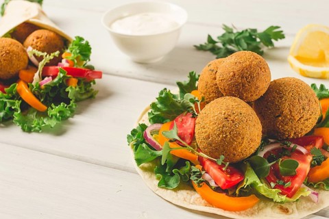 Tortillas, wrapped falafel balls, with fresh vegetables, vegetarian healthy food, on a wooden white