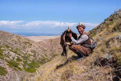 Traditional Kyrgyz eagle hunter with eagle in the mountains, near Kysyl-Suu, Kyrgyzstan, Asia