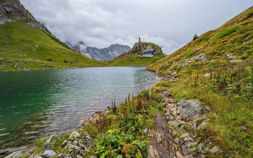 View over the mountain lake Wolayersee to the alpine club hut Wolayerseehütte, cloudy mountain