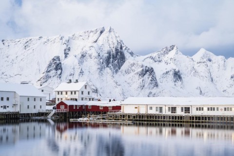 Rorbuer huts of Hamnoy at the fjord, snowy mountains in the background, Hamnoy, Reine, Moskenesoya,