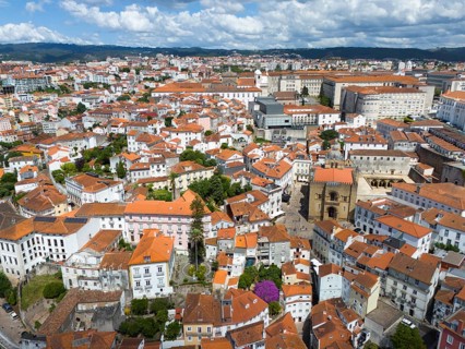 Dense urban environment with old red tiled roofs and historic architecture under a cloudy sky,