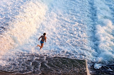 Girl bathing in the spray of the Lech weir, jumping into the white foaming water of the cascades,