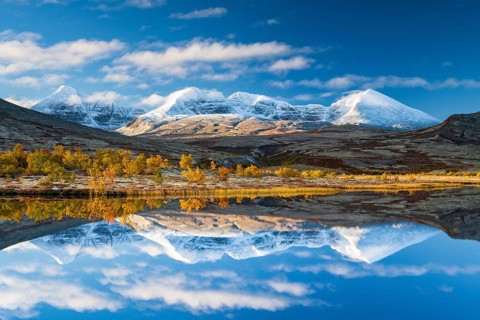 Reflection of the autumn landscape in Rondane National Park, snow-capped mountains, Doraldalen,