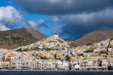 View of the town of Ermoupoli with pastel-coloured houses and sea, on the hill Basilica of San