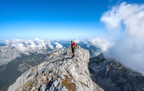 Mountaineer on a rocky narrow mountain path with mountain panorama, mountain tour to the summit of