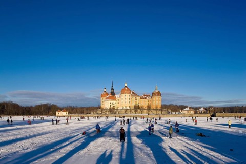 Moritzburg, castle park in winter with ice skaters on the frozen castle pond