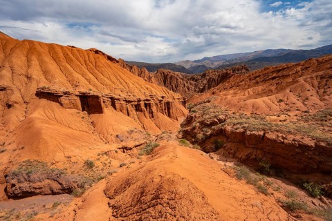 Eroded mountain landscape with sandstone cliffs, canyon with red and orange rock formations,