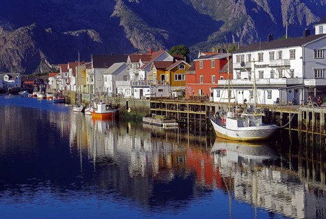 Fishing boats and wooden houses reflected in the small harbour of Henningsvaer, fishing, evening