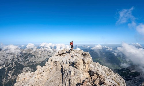 Mountaineer on a rocky narrow mountain path with mountain panorama, mountain tour to the summit of