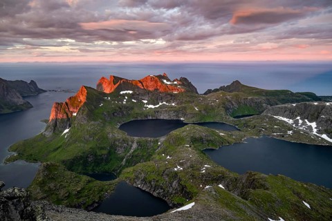 View over mountain peaks and sea, dramatic sunset, from Hermannsdalstinden, with lakes