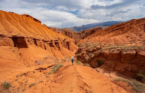 Mountaineer on a mountain ridge, view of eroded mountain landscape with sandstone cliffs, canyon
