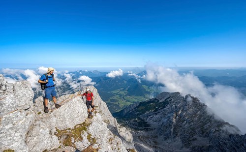 Mountaineer on a rocky narrow mountain path with mountain panorama, mountain tour to the summit of