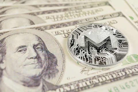 MONERO XMR cryptocurrency, silver monero coin on the background of Dollar bills