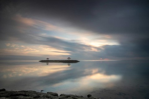 Beautiful seascape in the morning. Tropical sandy beach with breakwater and reflection of the sky