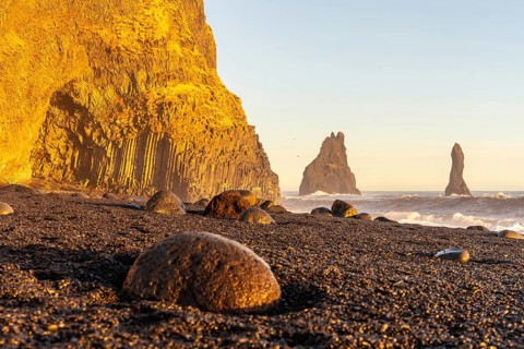 Beautiful on the black sand beach of Reynisfjara at sunset in Iceland