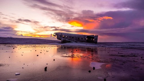 Beautiful aerial drone view at sunrise on crashed plane on frozen Solheimasandur beach in winter,